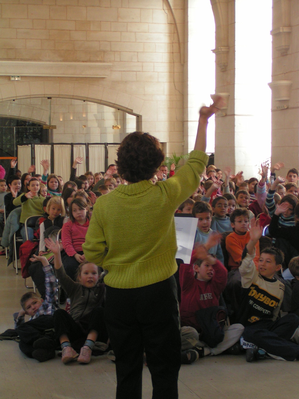 Petra devant une salle pleine d'enfants qui lèvent la main